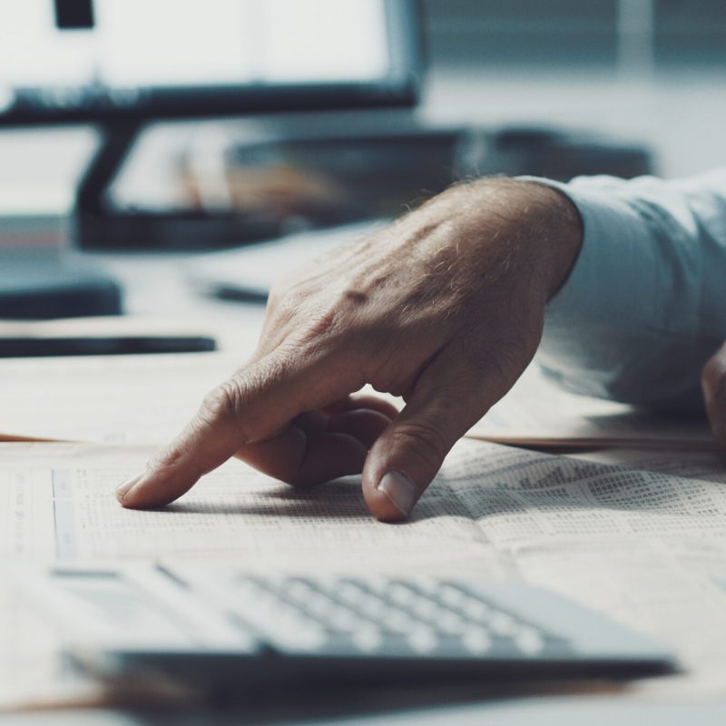 Businessman checking stock market news on a financial newspaper