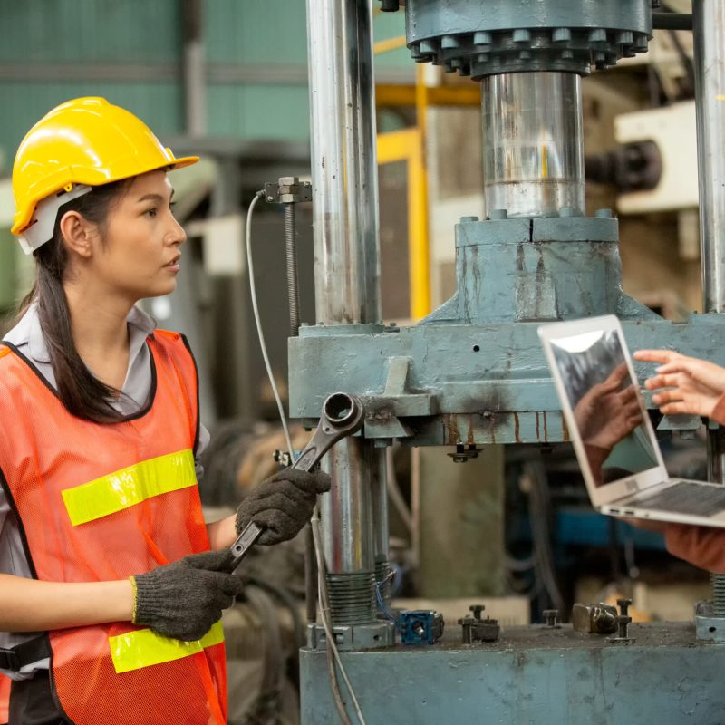 Hard-working engineer holding digital tablet in hands while working in manufacturing plant, profile view